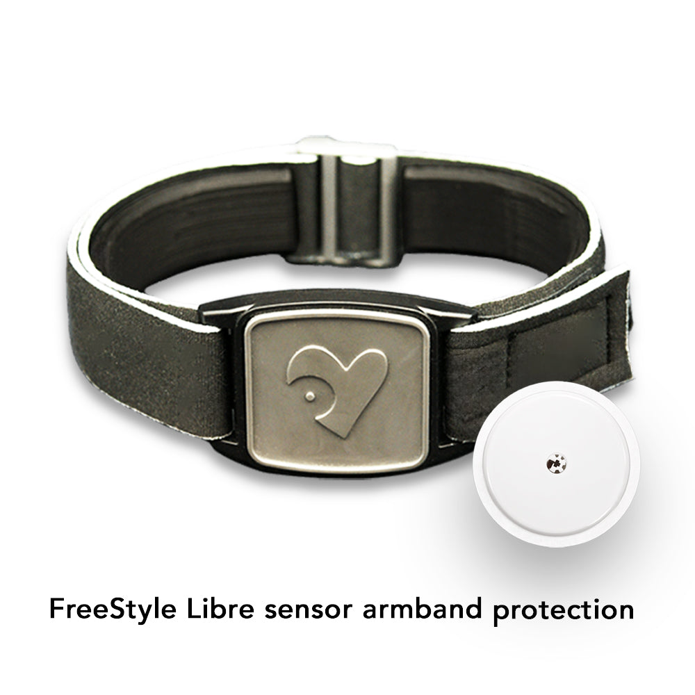 A stylish Freestyle Libre 2 CGM sports and swim armband with a pewter heart design on a neoprene strap, displayed by a poolside.
