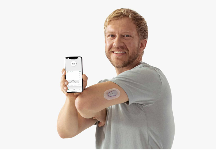 Man showing glucose level on phone and wearing Dexcom CGM on arm.