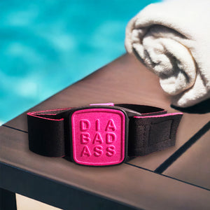 Dexband CGM armband for Dexcom G7 and ONE+ sensors with magenta DIABADASS cover and water-resistant neoprene strap on wooden lounger in swimming pool setting