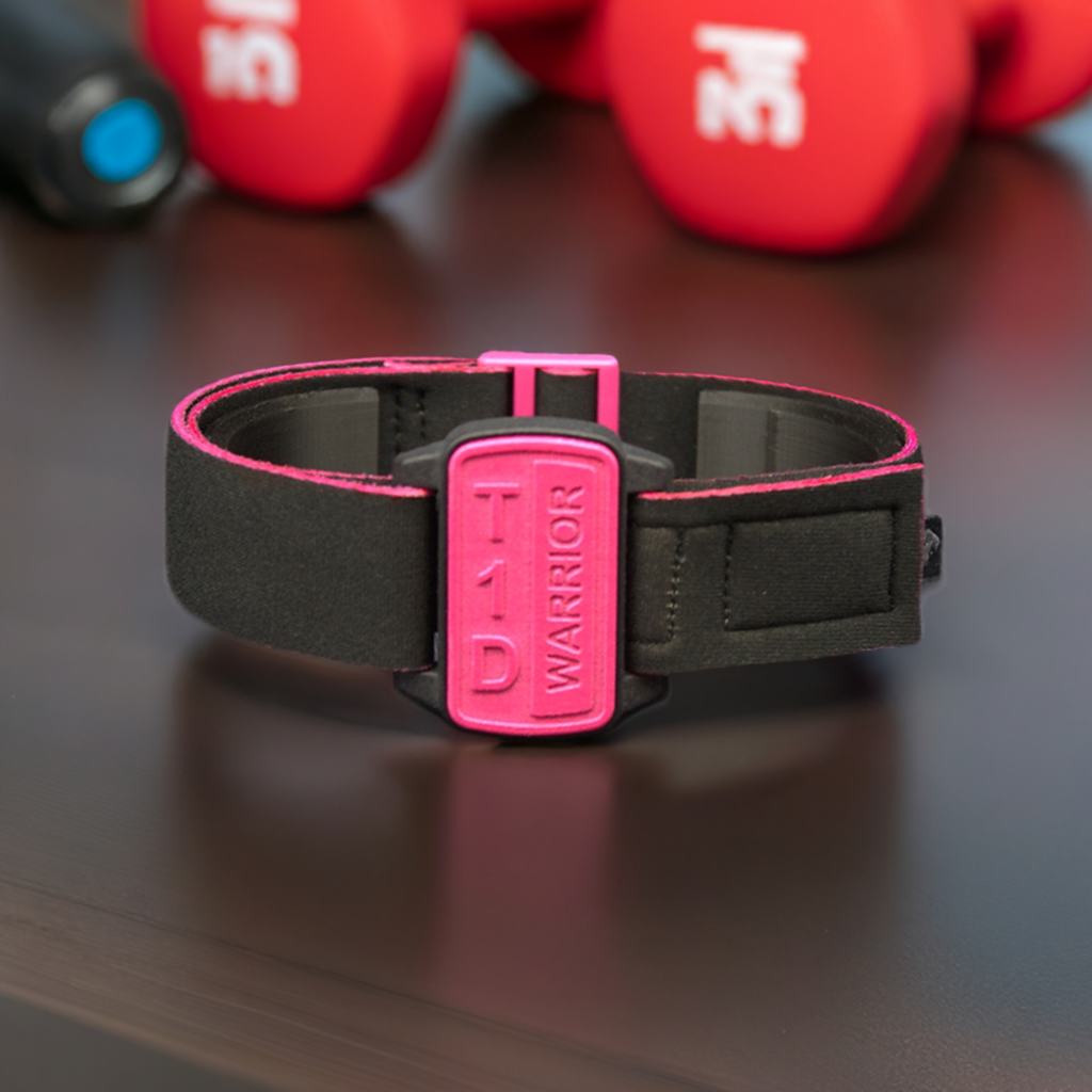 Dexband armband cover in magenta with motif T1D Warrior. Black strap edged in coordinating magenta. Shown on dark wooden surface next to gym equipment.