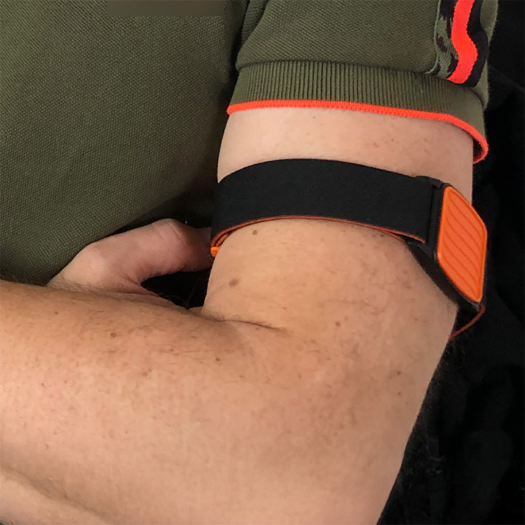 Closeup of Libreband armband worn on upper arm covering Freestyle Libre CGM. Orange cover with Wave design and black strap.