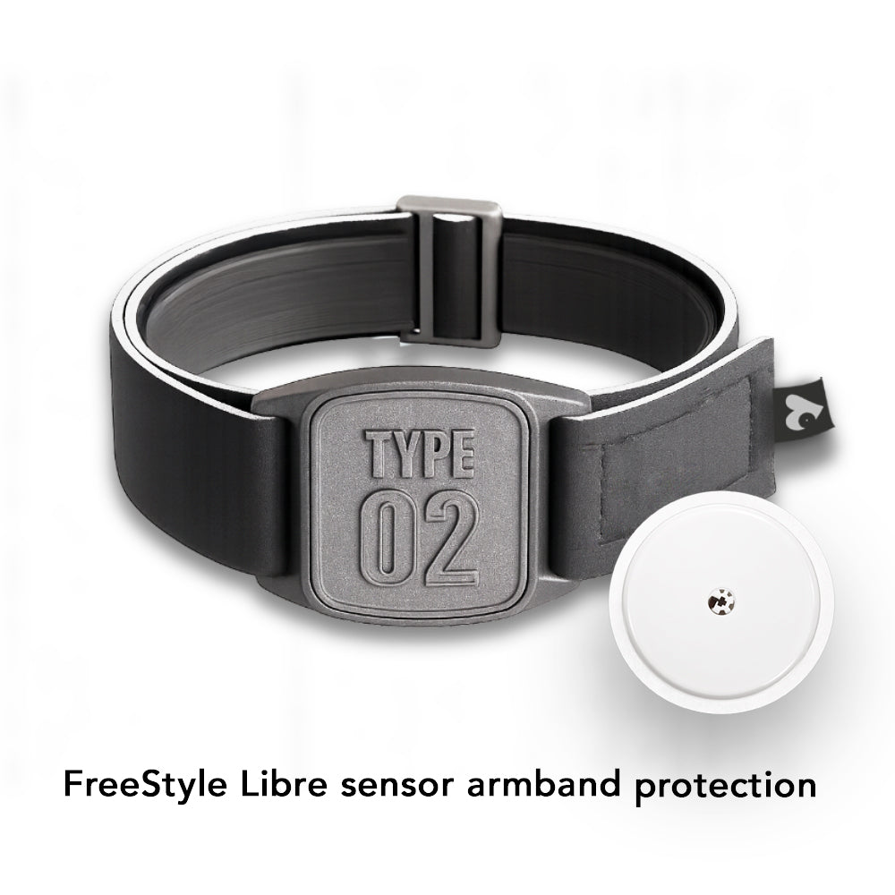 A pewter-colored neoprene armband with a 'TYPE 02' design, branded as Love My Libre Ltd, intended for use with a Freestyle Libre CGM. The armband is displayed on a wooden surface with a pool in the background.