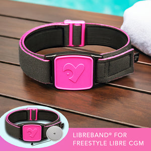 Libreband CGM armband for FreeStyle Libre 2 with magenta heart cover and water-resistant neoprene strap on wooden lounger in swimming pool setting. LML2388, LML2371, LML2920, LML4481. 