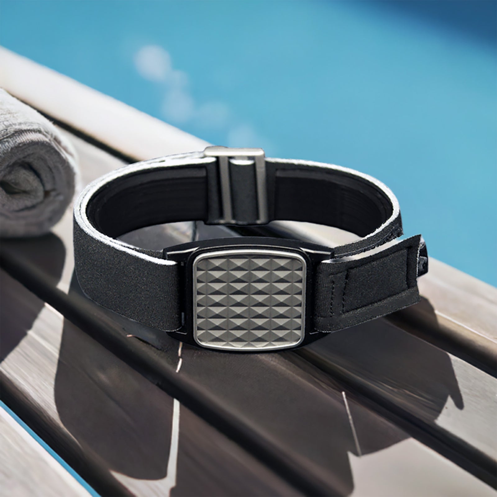 Libreband CGM armband for FreeStyle Libre 2 with pewter pyramids cover and water-resistant neoprene strap on wooden lounger in swimming pool setting. LML4634, LML2906, LML2616, LML2623.
