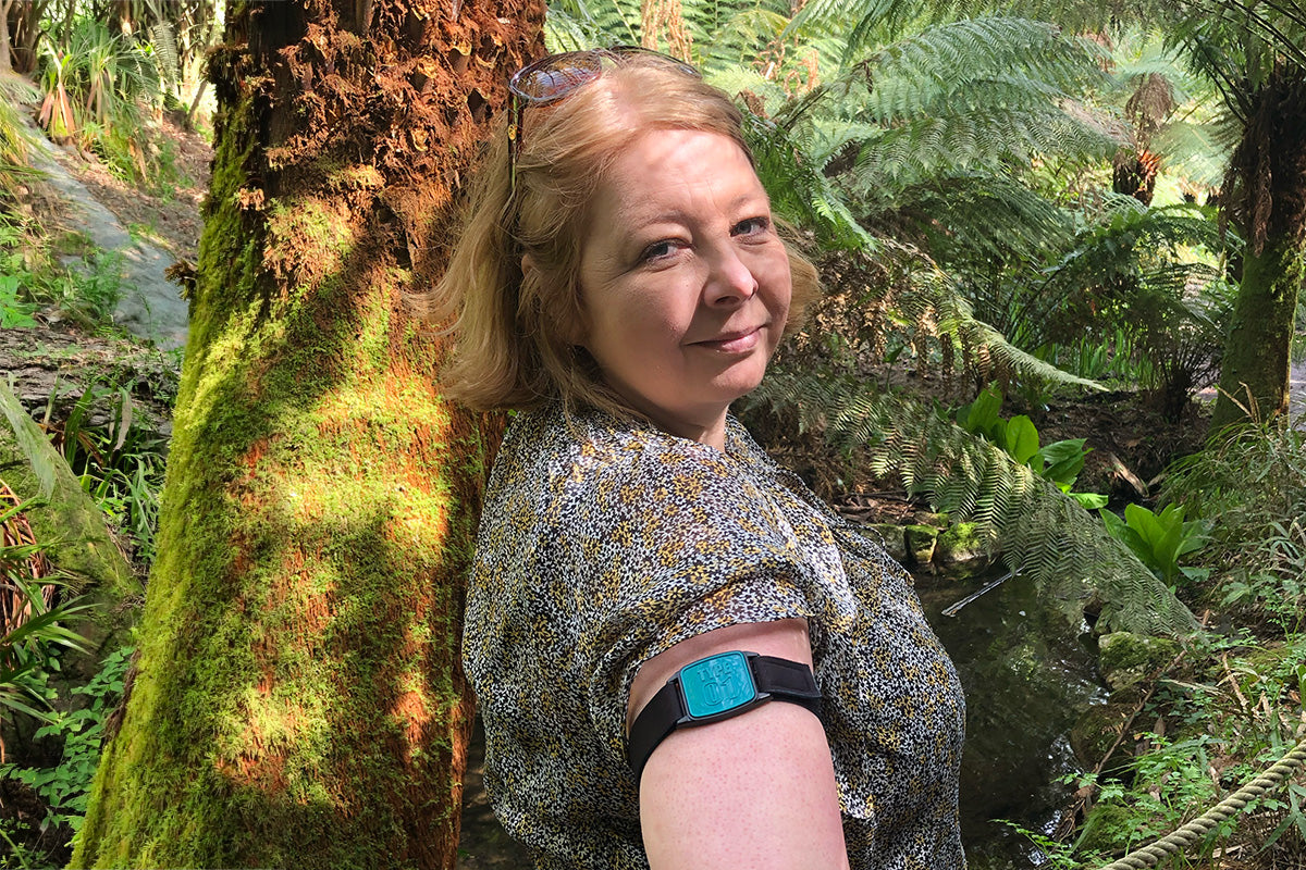 Libreband CGM armband with teal cover on female in gardens